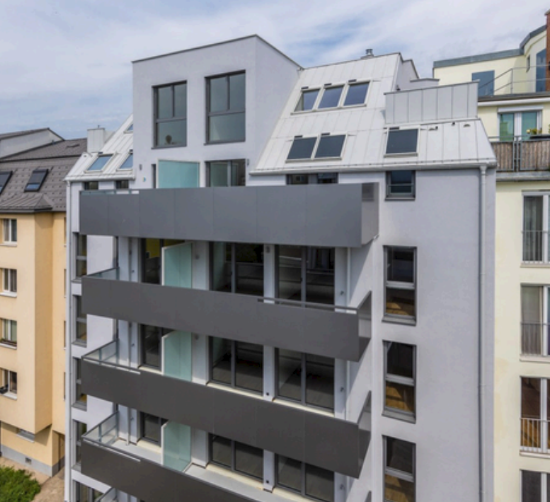 Modern multi-storey residential building at Pilzgasse, Vienna, with grey facade and balconies.